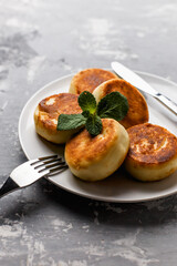 Sweet cottage cheese, tasty curd cheese fritters, Syrniki on gray background