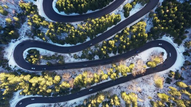 Drone 4k clip bird's eye perspective of a beautiful winding mountain road in Romania in winter time 