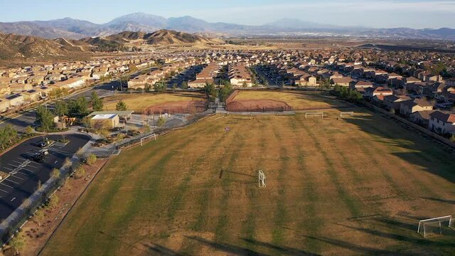 Wide aerial shot of athletic fields and recreation center in a desert master-planned community. HD at 60 FPS.