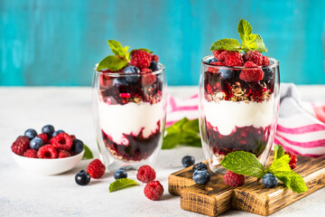 Parfait with yogurt, granola, jam and fresh berries in the glass jar. Healthy dessert or snack.