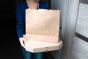 Young woman holding blank cardboard pizza box and paper shopping bag. Delivery concept