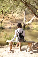Mujer sentada de espaldas, no se le ve la cara, mirando el lago
