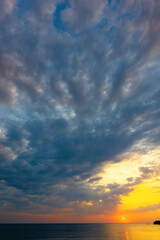 dynamic cloudscape in summer at sunrise. dark clouds on the sky in yellow and pink morning light. dramatic weather condition, picturesque scenery above the sea