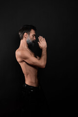Fototapeta na wymiar guy with a beard with a sports figure, with a naked torso on a black background