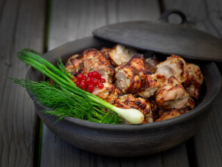 Grilled marinated chicken shashlik pieces in a bowl with greens