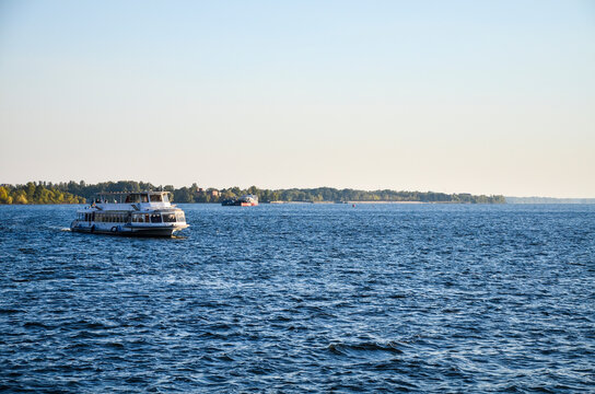 Tourist pleasure boat floats on the river Dnipro in the city Zaporizhya at sunset. Weekend walks.