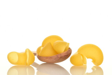 Bright yellow uncooked pasta with a wooden spoon, close-up, isolated on white.