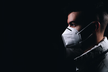 Ciudadano con mascarilla iluminado con luz frontal y de contra en fondo negro