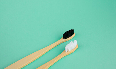Natural bamboo toothbrushes with white and black bristles on a mint green background. The concept...