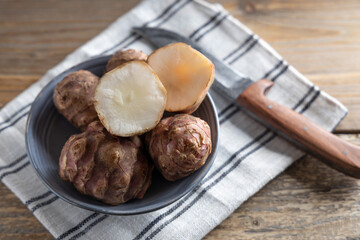 Trendy Winter vegetable. Jerusalem artichoke one of the forgotten vegetables who has become trendy again, on a wooden table.