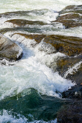 Water rushing over the large rocks in Ohiopyle State Park in Pennsylvania. Portrait orientation.