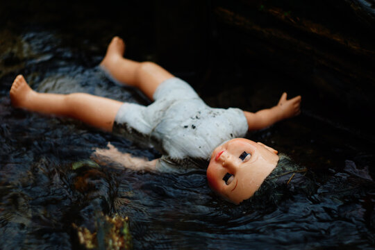 Corpse of a dead doll floating in water