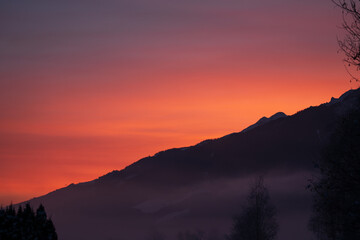 beautiful sunrise with orange and pink sky in the mountains and fog in the valley