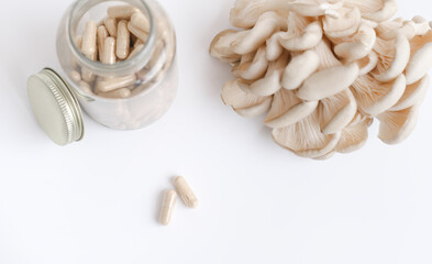 mushrooms and a bottle with mushroom capsules supplement on a table. antioxidant and detoxifying nutritional supplement. vegan superfood. selective focus