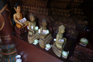 Marble Buddha statue carrying a banknote offering and a lotus flower, interior of pagoda of Buddhist Wat Phnom temple, Phnom Penh, Cambodia
