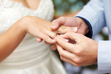 Exchange Of Wedding Rings. Wedding ceremony. Groom puts on golden wedding ring to bridal's finger, closeup. Bride and groom, newlyweds.