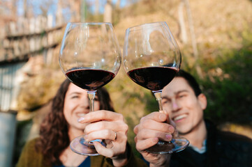 Close-up two glasses of red wine with smiling couple in the background. People having an outdoor...