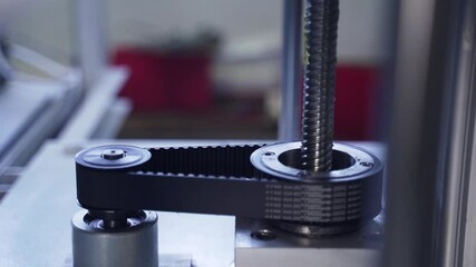 Reasonable belt on machine revolves around shaft. Iron gears and toothed shaft rotate in machine