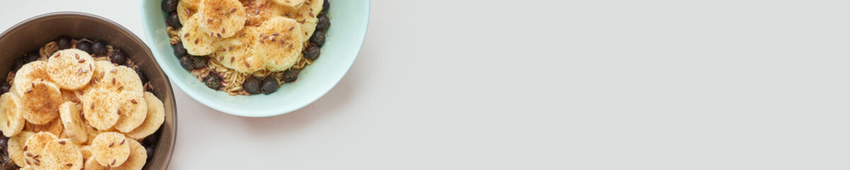 Healthy breakfast. Top view. Oatmeal with banana and flax seeds at bowl. Berry in plate. Organic meal recipe. Vegan cook. Minimalism granola. Hot porrigde with fruit. Banner, copyspace