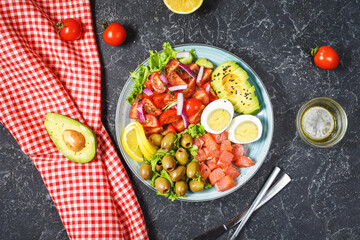 Ketogenic, paleo diet lunch bowl with salted salmon fish, lemon, avocado, olives, boiled egg, tomato, green lettuce salad, healthy food trend