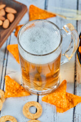A glass of beer and chips on blue table, close up