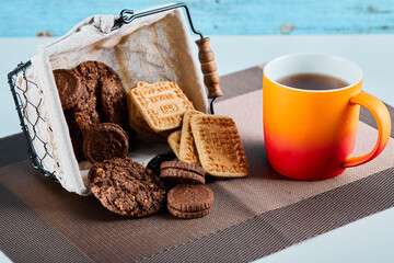 Assorted biscuits, candies and a cup of tea on gray background