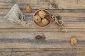 Left composition. Walnuts, a bag, cinnamon and a fir cone on the background of old wooden boards. High quality photo vintage style