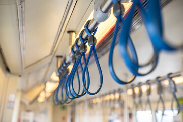 Row of blue safety hanging straps grab handles inside a metro train