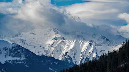 beautiful view of the snow capped hohe tauern in austria on a sunny winter day with foehn storm on the mountains