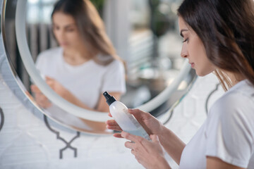 Young woman studying ingredients of the hairspray