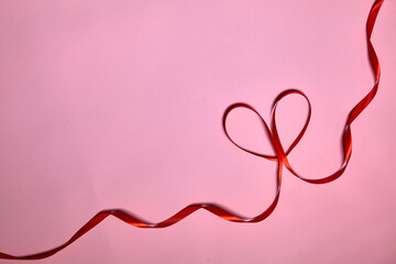 Heart made of red ribbon on pink background, top view. Festive decoration. Heart shaped Ribbon. Valentines day greeting card