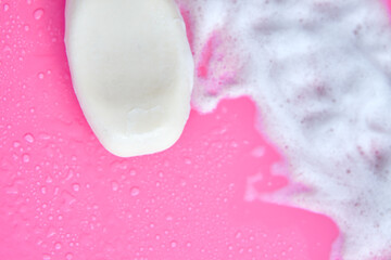 Washing concept. Foam bubbles and brick of soap on pink background. Cleaning service