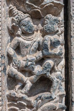 Lakkundi, Karnataka, India - November 6, 2013: Kasivisvesvara Temple, Gray stone defaced dancing couple sculpture on outside wall.