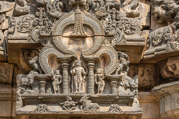 Lakkundi, Karnataka, India - November 6, 2013: Kasivisvesvara Temple, Brown stone fresco sculpture on outside wall showing Shiva and family in decorative setting. All gods defaced.