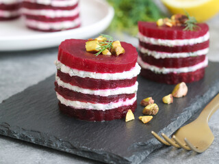 A plate of layer red beetroot napoleon and goat cheese appetizer salad with roasted pistachio and...