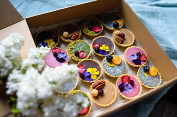 Selection of colorful and delicious cake desserts in box on table, top view.