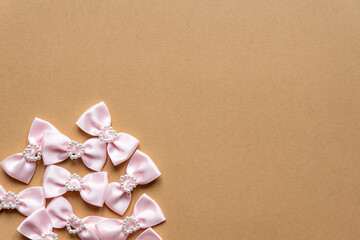 Pink satin bows with pearl hearts pattern on beige background. Festive concept for St Valentine's Day