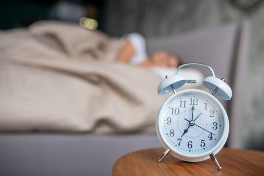 White mechanic alarm cloch standing near the bed
