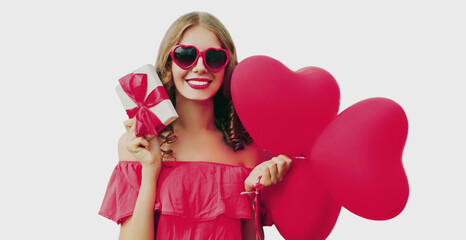 Portrait of happy smiling woman with gift box and pink heart shaped balloon on a white background