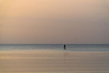 Fototapeta na wymiar A man with an oar swims standing on a board on the Gulf of Finland.