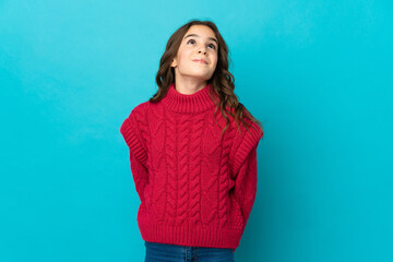 Fototapeta premium Little caucasian girl isolated on blue background and looking up