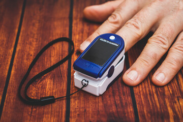 Small digital device for measuring pulse and blood oxygen level. Oximeter on a man's finger. The realities of the coronavirus pandemic.