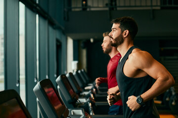 Two young man running on treadmill at gym