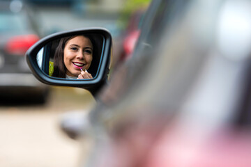 Fototapeta na wymiar teenager driver applying lipstick using rear mirror in a car