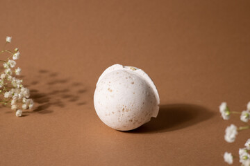 Vanilla aroma bath bomb in spa composition with dry flowers on brown background. Aromatherapy...
