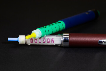 two insulin syringe pens for hormone therapy of patients with diabetes mellitus, close-up, on a black background