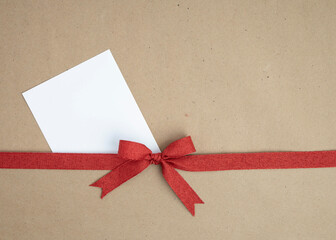 Brown kraft paper background for text, invitations, signs or holiday greetings with red fabric ribbon from above