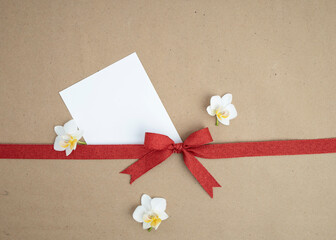 Brown kraft paper background for text, invitations, signs or holiday greetings with red fabric ribbon from above