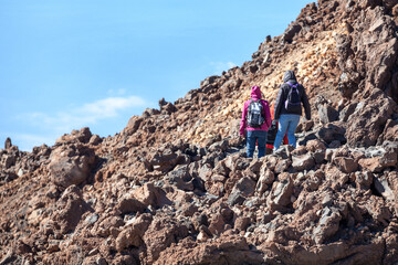 Team of hikers climbing to volcano summit on route No. 10 among the hardened lava flows and shape boulders. Hiking trail to the crater of Teide, Spain's highest peak.