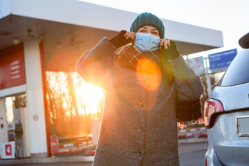 Young woman wearing medical mask at gas station